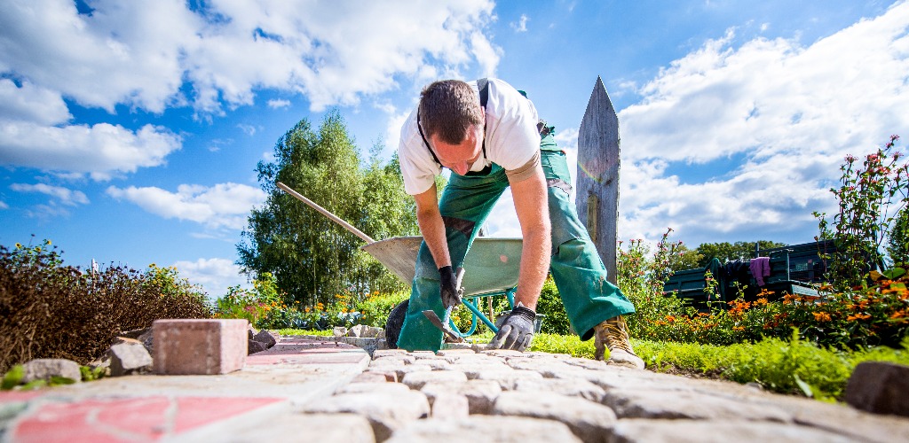 Handwerker verlegt Pflastersteine in einer Gartenanlage